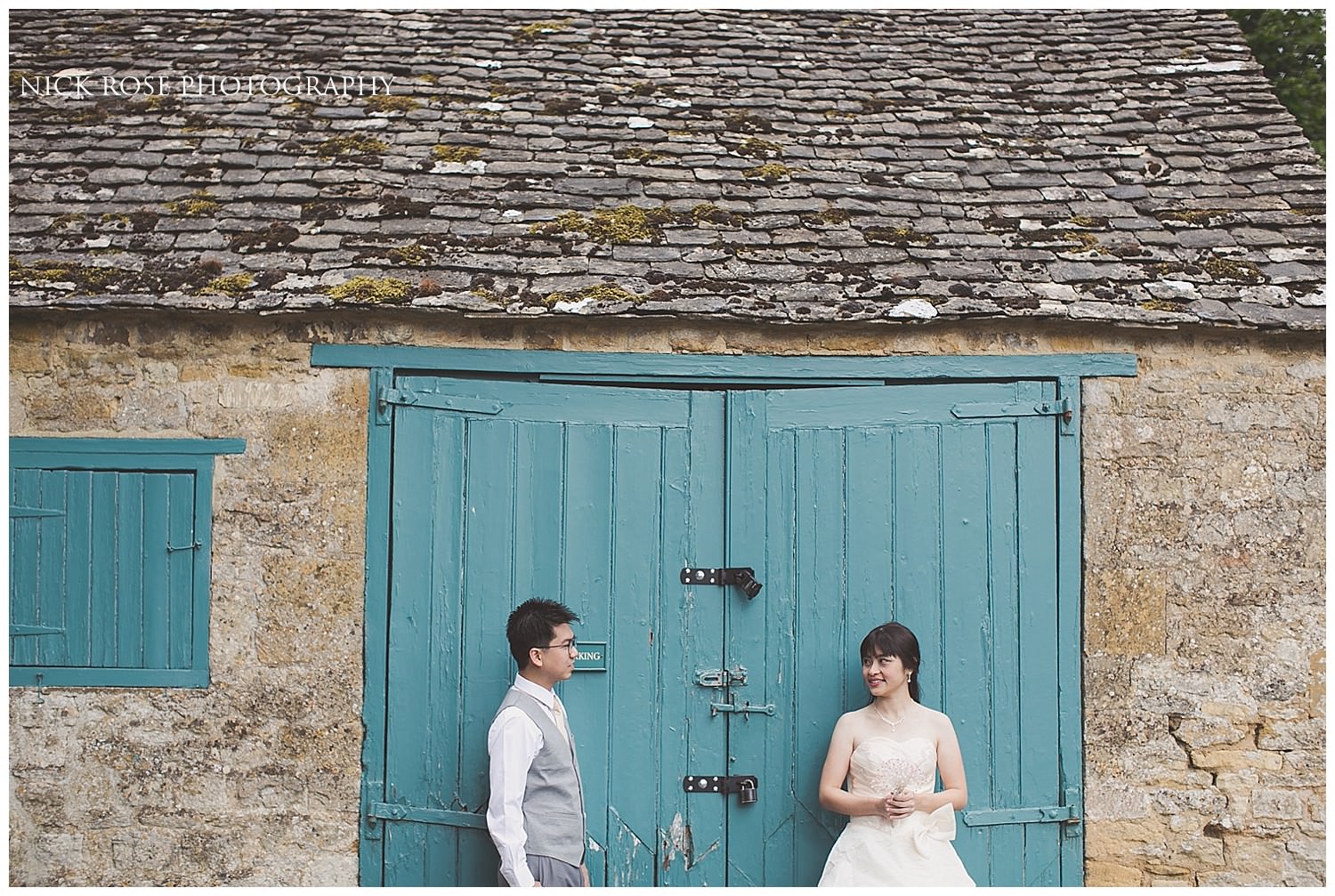  Pre wedding photograph of a couple in front of a green Cotswolds barn in Stanton 