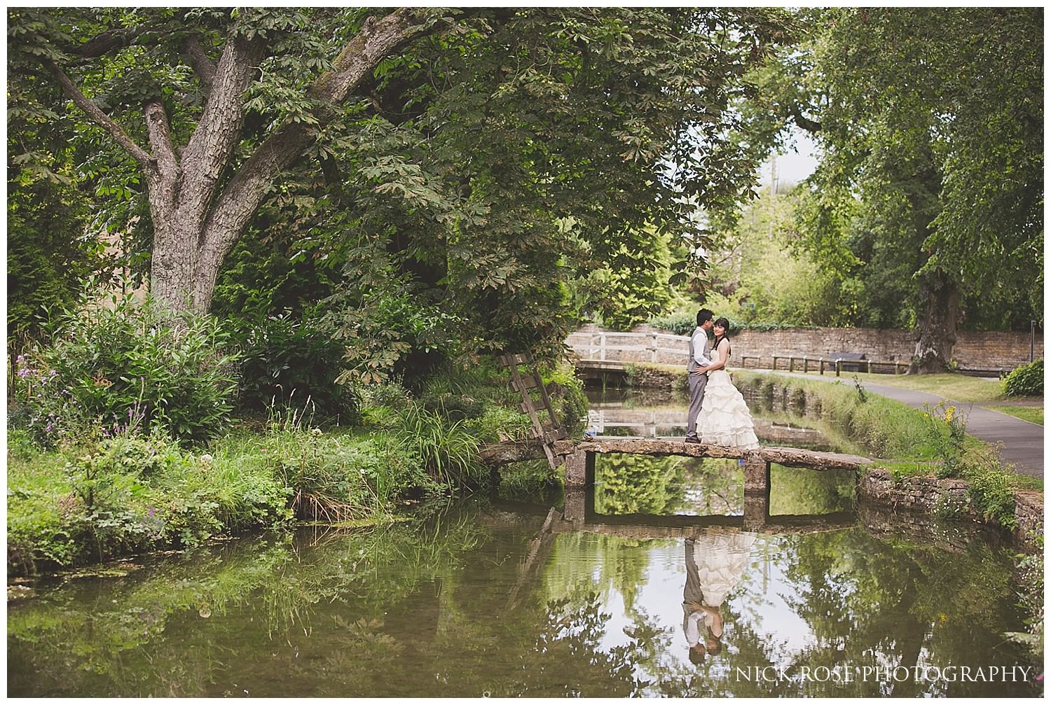  Reflection in a stream of a bride and groom in a wedding dress and suit during a pre wedding photography session in Lower Slaughter 