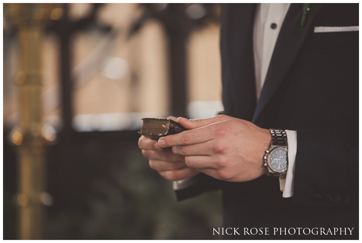  Groom holding a vintage bible before his wedding in London 