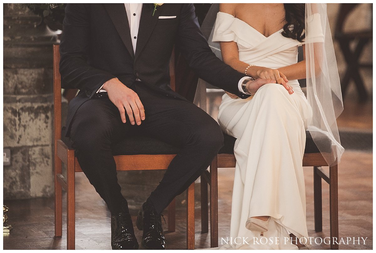  Groom and bride holding hands during a London wedding ceremony 