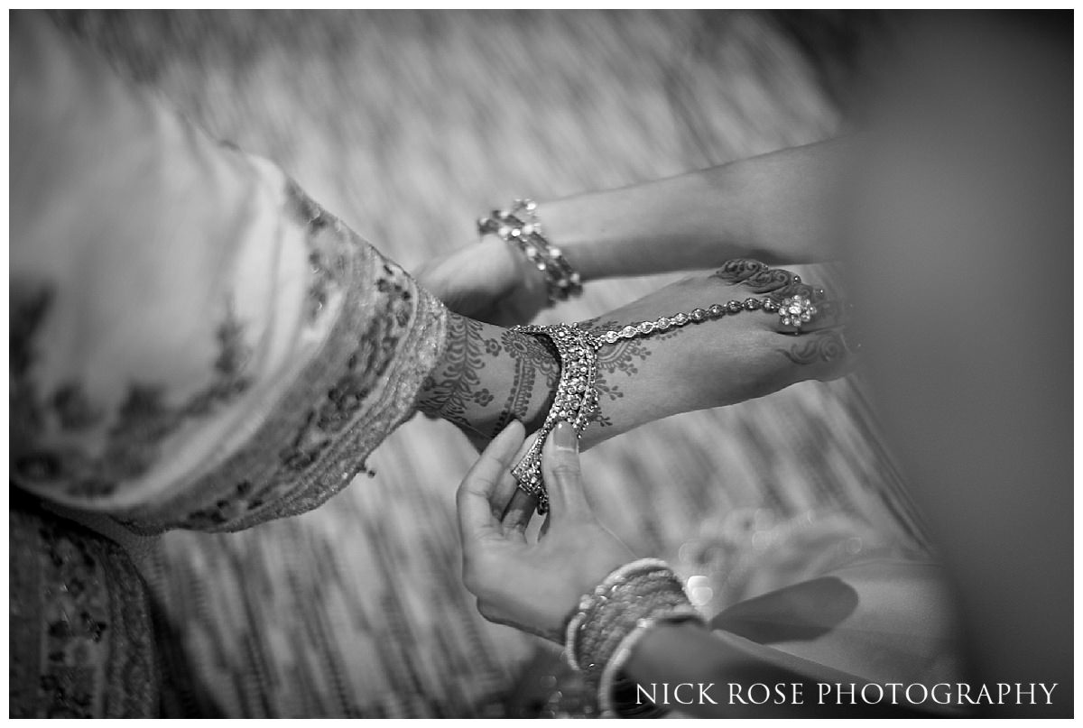  Indian bride having her wedding shoes put on by bridesmaid before a wedding at the Grove 