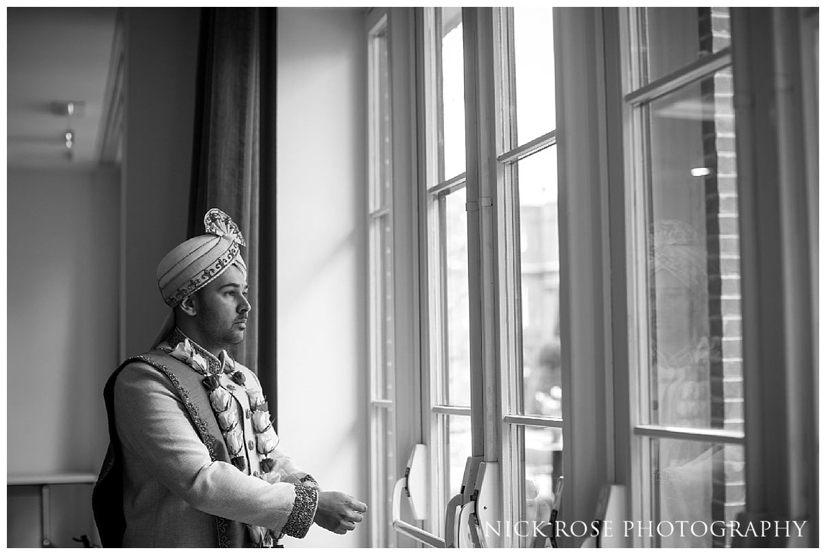 Indian groom standing by the window before his Asian wedding ceremony in Hertfordshire