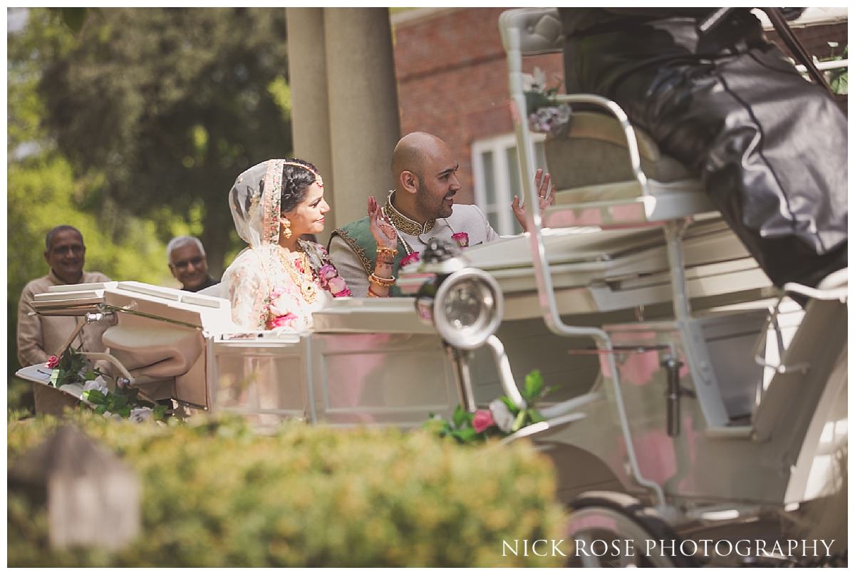  Bride and groom exiting a Hindu wedding at The Grove in Hertfordshire on a horse and carriage 