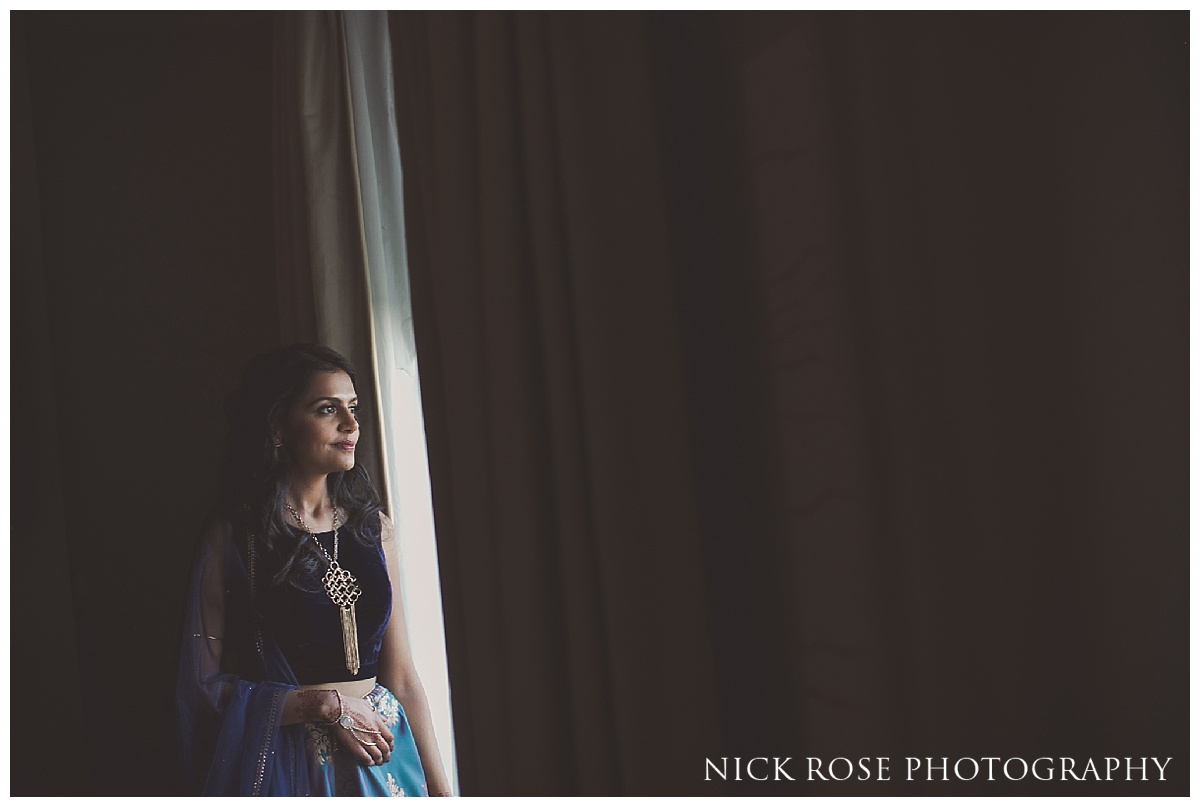  Indian bride getting ready and looking out of the window at The Grove in Watford, Hertfordshire 