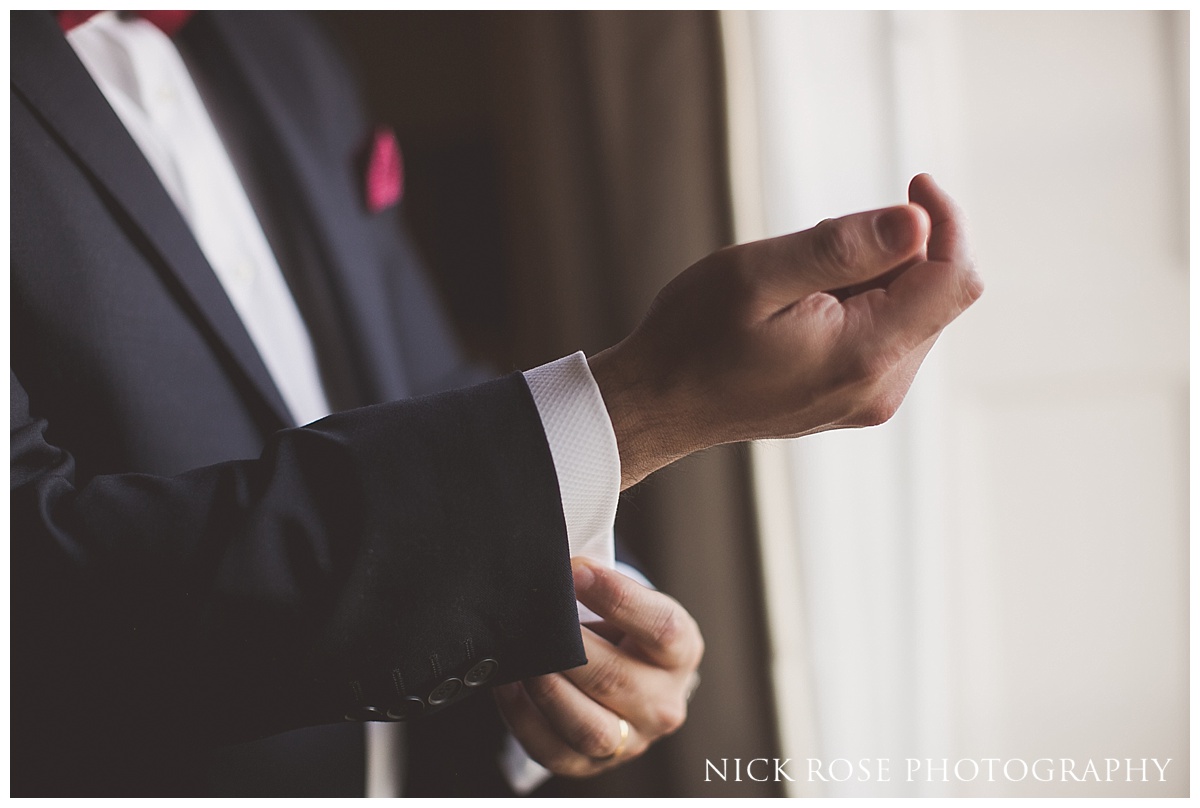  Groom putting on cufflinks for a Hindu wedding reception at The Grove in Watford 