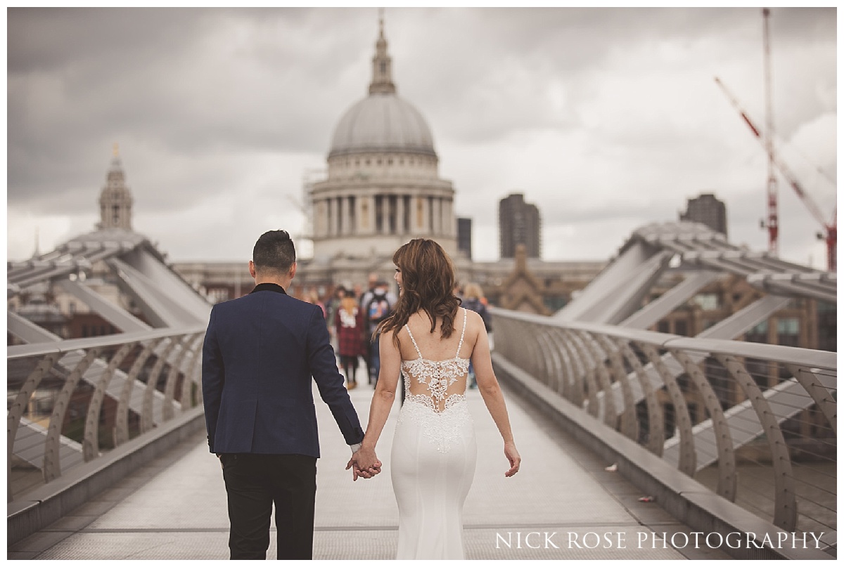  Couple walking over Millennium Bridge and golding hands for a pre wedding shoot in front of St Pauls Cathedral on London 