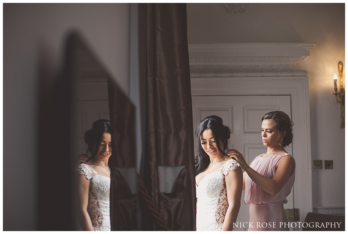  Bride putting on dress for a Buxted Park hotel wedding in East Sussex 