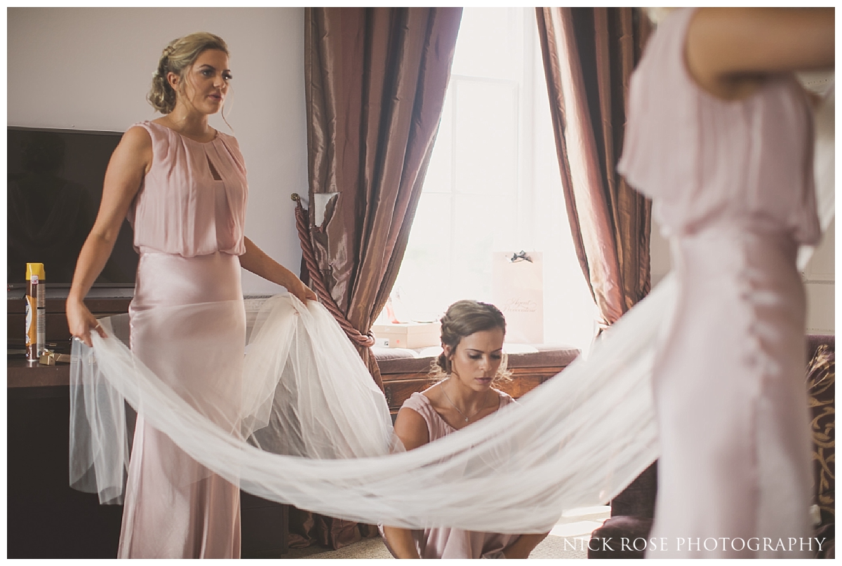  Bridesmaids putting on brides veil before her Buxted Park hotel wedding in East Sussex 