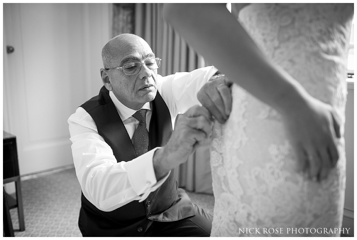  Brides father helping to put on daughters wedding dress for a central London wedding at Dartmouth House in Mayfair 