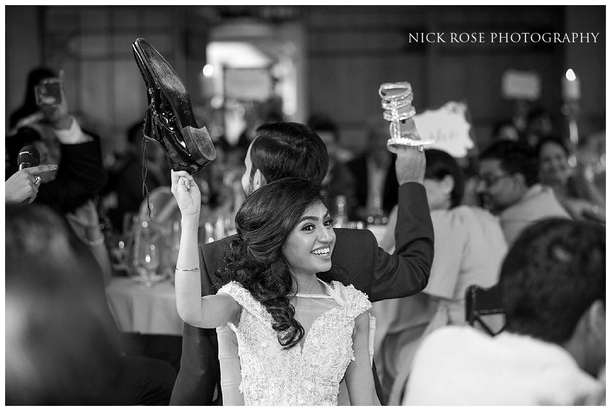  Bride and Groom playing the fun shoe game during a Sikh civil wedding reception in Buckinghamshire 