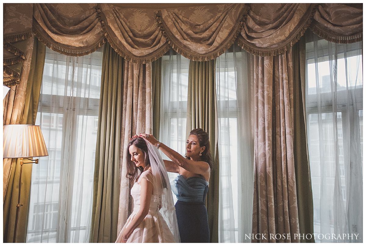 Brides mother helping her daughter get ready for a Savoy London wedding