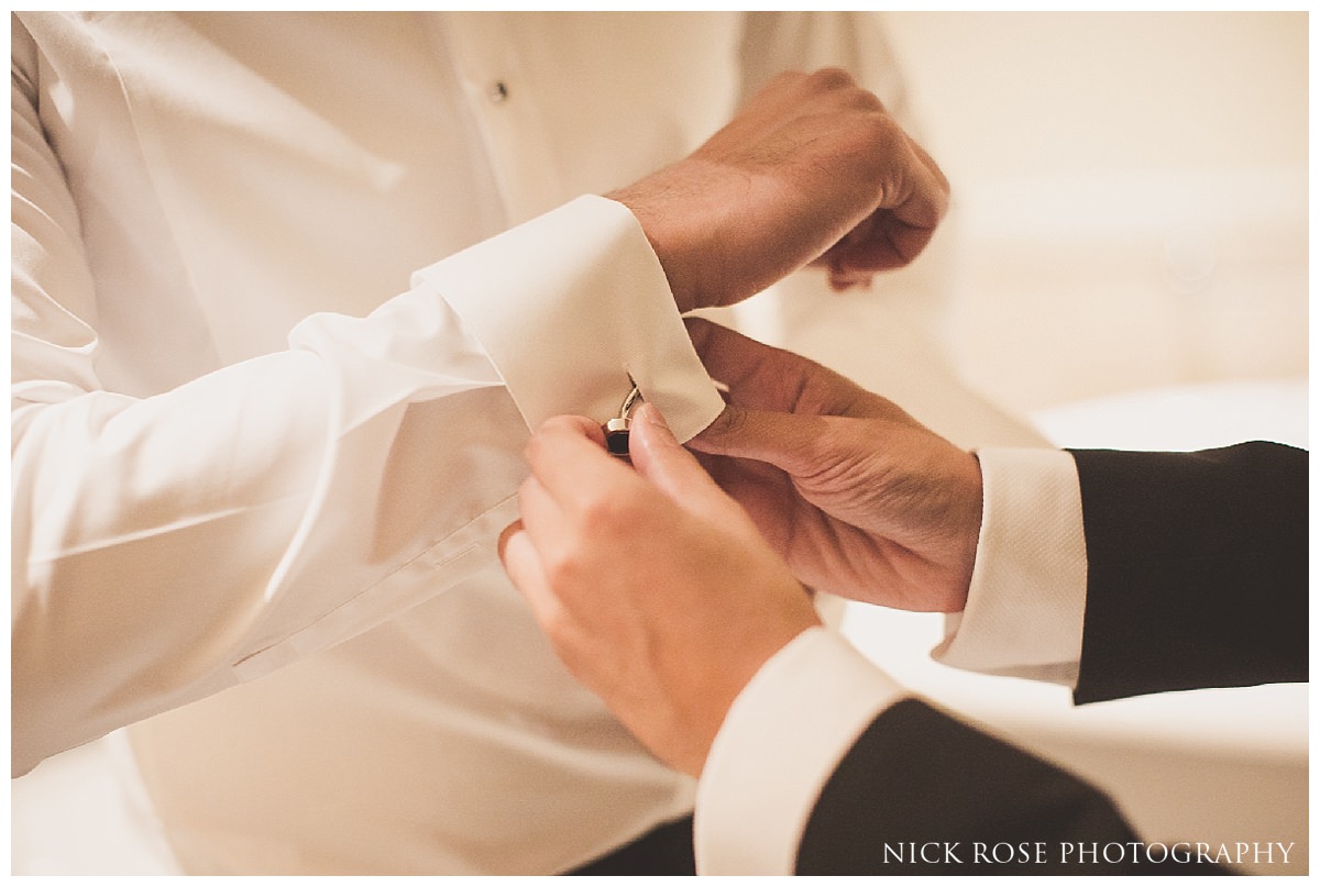  Groom putting cufflinks on before a Savoy London wedding 