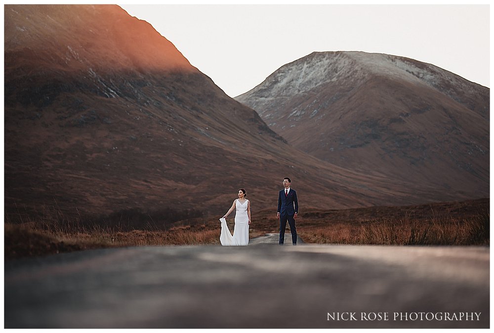  A couple standing on a road in Glencoe Scotland for a destination pre wedding elopement shoot in the Highlands 