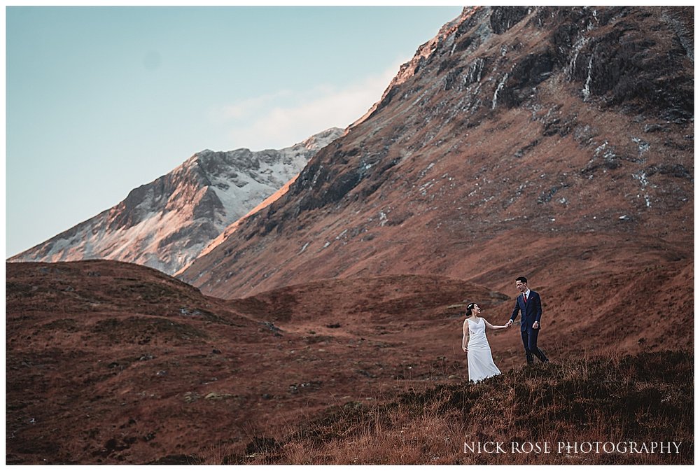  A couple standing on a rocky outcropping, taking in the panoramic view of Glencoe's valleys and hills. 
