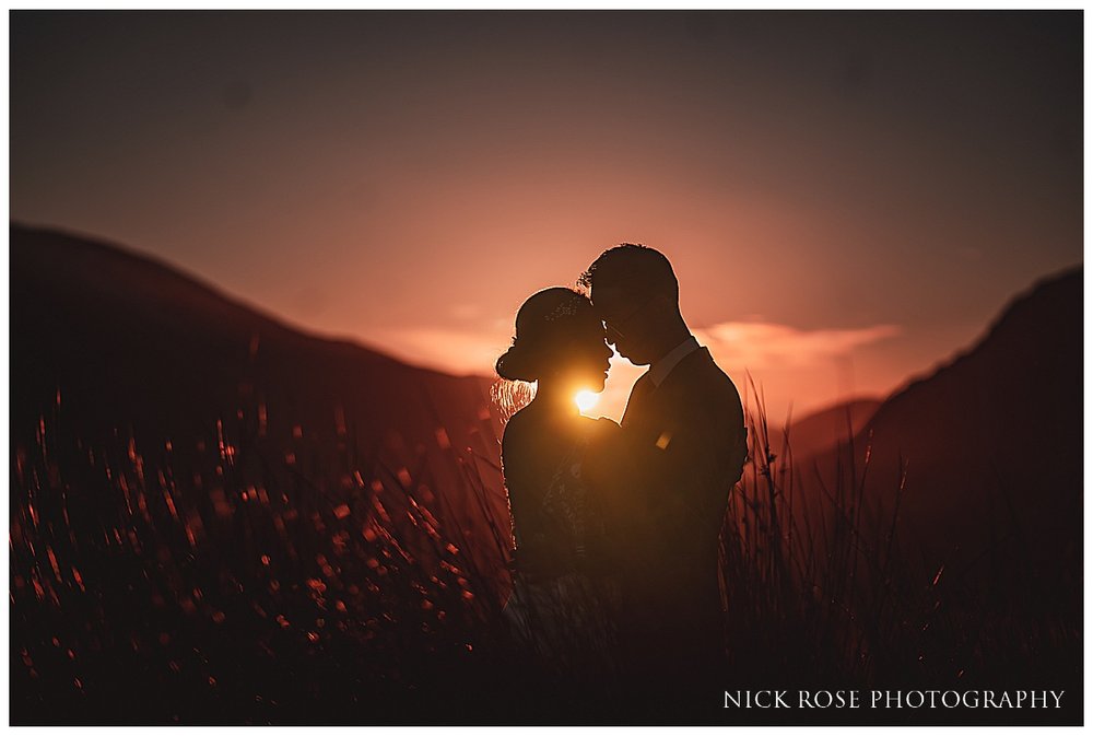  A romantic shot of a couple embracing on a hillside in Glencoe, surrounded by mountains. 