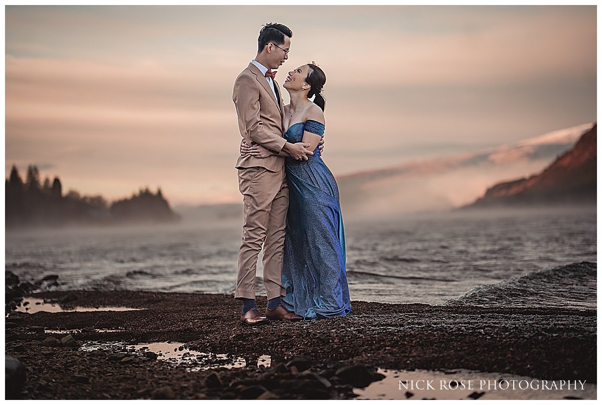  A shot of a couple standing on the shores of a tranquil loch, surrounded by the stunning landscape of Glencoe. 