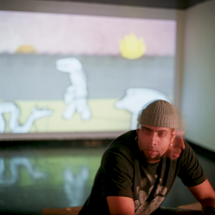 Sitting in front of one of his animations, Cox, prefers the layers of mythology that evolve within his pieces as well crafting the pieces that perform in the animations. Photo © Aimee Santos