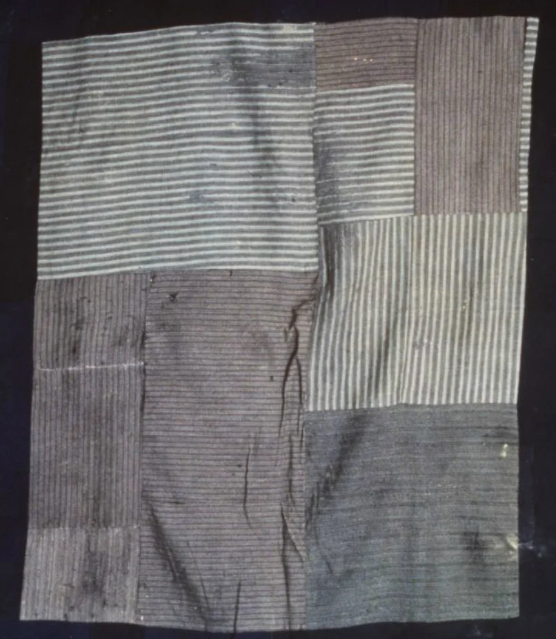 Quilt, "wagga", patchwork, wool, Kathleen Parker, Woonona, NSW, 1936 "Wagga quilt, machine-pieced from old woollen suiting fabrics; some hand stitching is visible along a few of the joins. The quilt has three layers. The top layer has a rectangular centre of different grey fabrics, pieced together randomly, and the border is made up of irregular rectangles of navy blue fabrics. The backing is of striped cotton, and the lining is made of corn bags. The three layers are machine-stitched together at the edges, holding the filling in place. There is no quilting. The quilt is in reasonable condition, though through its years of use there are some stains and holes and some areas where the material is thinning."  Read more : http://www.powerhousemuseum.com/collection/database/?irn=53867#ixzz3fw3W0lbi&nbsp; Under Creative Commons License: Attribution Non-Commercial