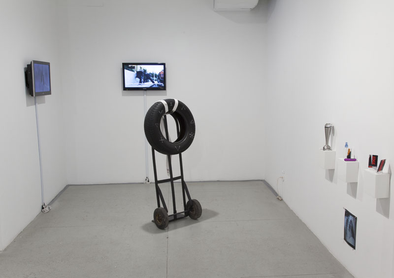   Jonathan Durham &amp; Francis Estrada,   Instructions for Surviving Edges , 2012-13. Installation with video, rubber tire, hand truck, rice bags, and “improvised” weapons. 