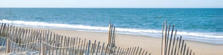 Mid day high tide at a narrow stretch of the beach, which overall is seven miles long and mainly very wide. Fences protect some of the white dunes.