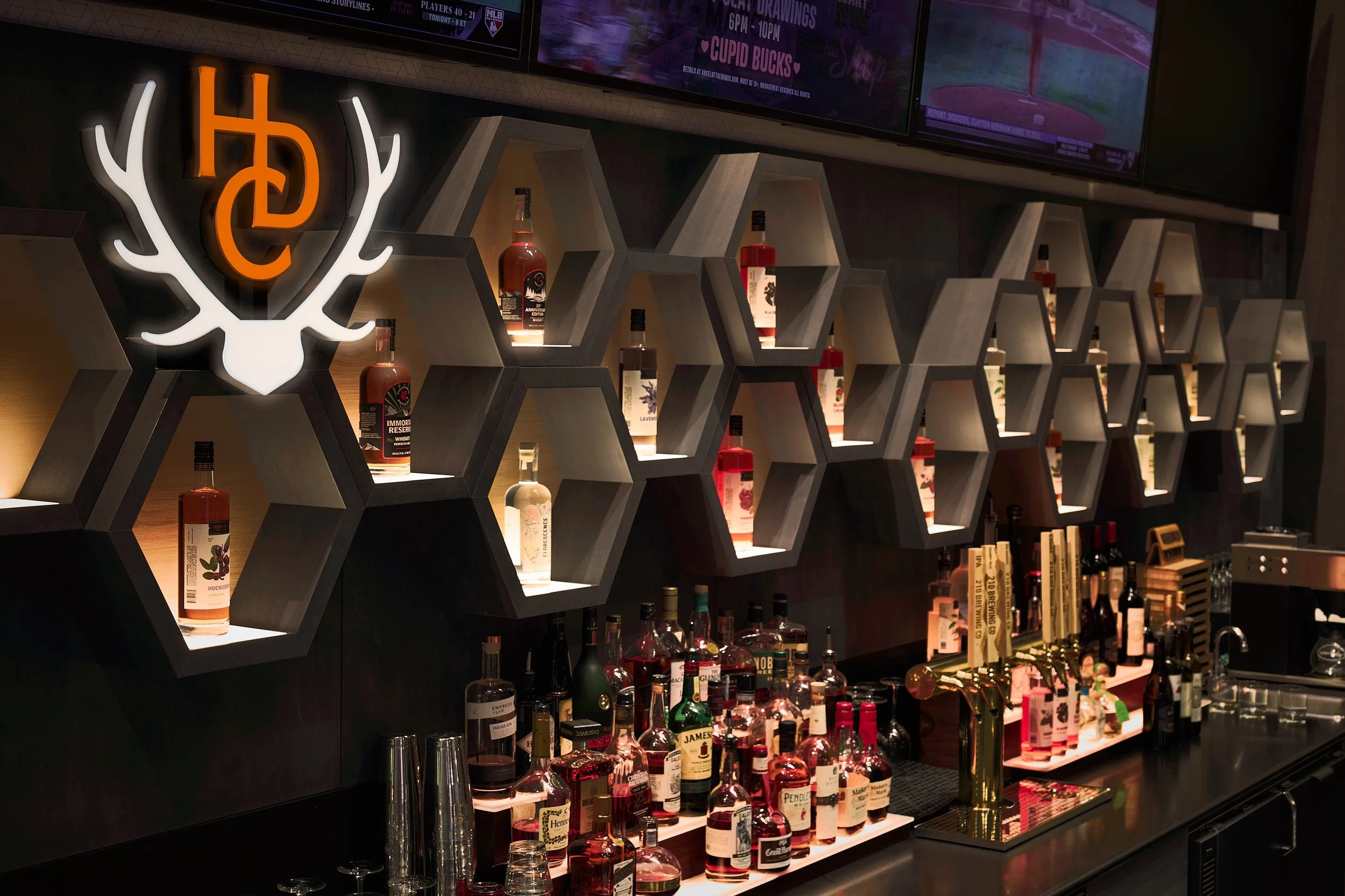 Tighter architectural detail of unique wooden backlit bottle display and custom millwork at Heritage Distilling tasting room, Angel of the Winds Casino Resort, designed by fi architecture.