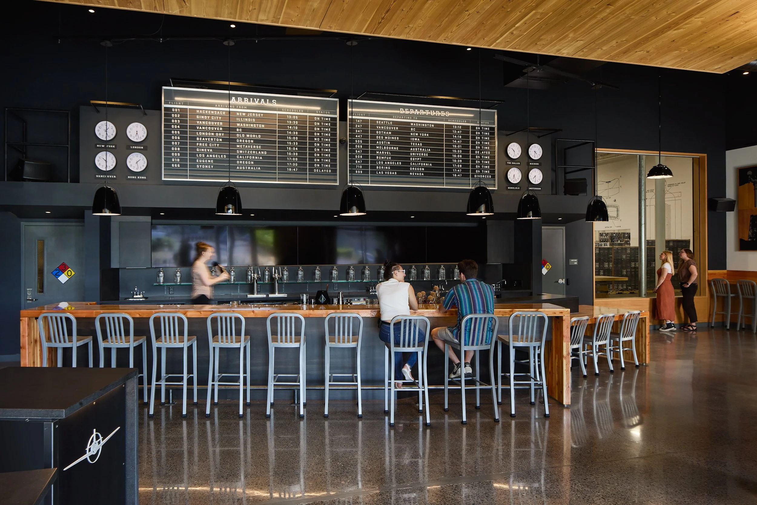 Interior architectural photography of the full service bar and patrons viewing the distillery operations at Aviation Gin Distillery in Portland, Oregon, designed by fi architecture.