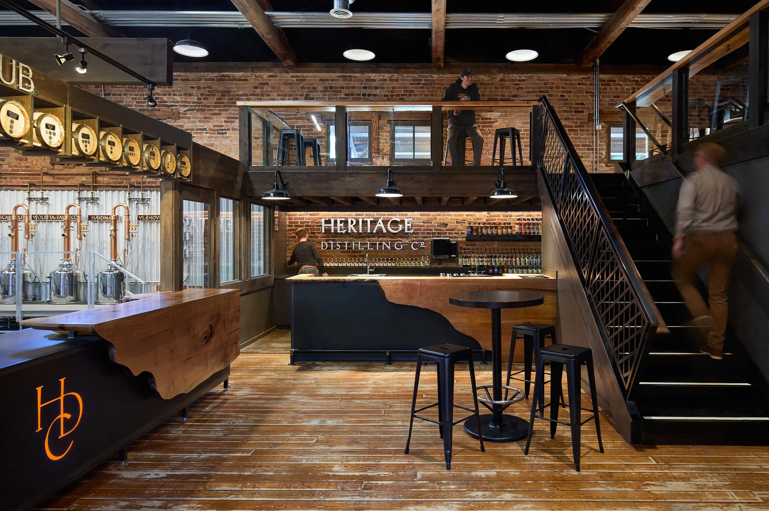 Full interior architectural photography showcasing the distillery, bar, and upstairs seating area at HDC Roslyn, Roslyn, Washington, designed by fi architecture.