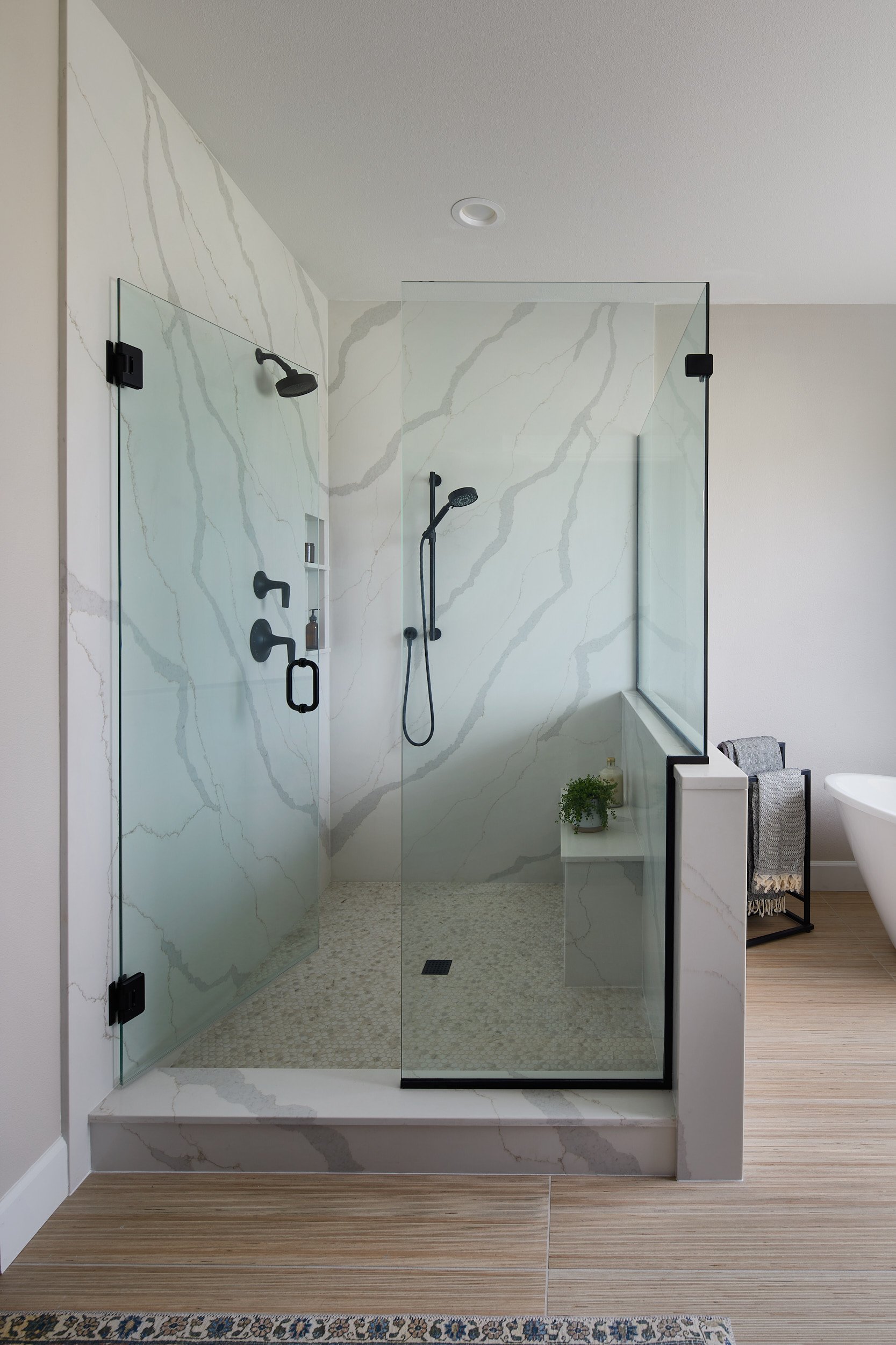 A custom marble shower and fixtures in an Eastside Olympia Residence, highlighting a built-in shower niche and high-end glass door, built by Brown Building Contractors.