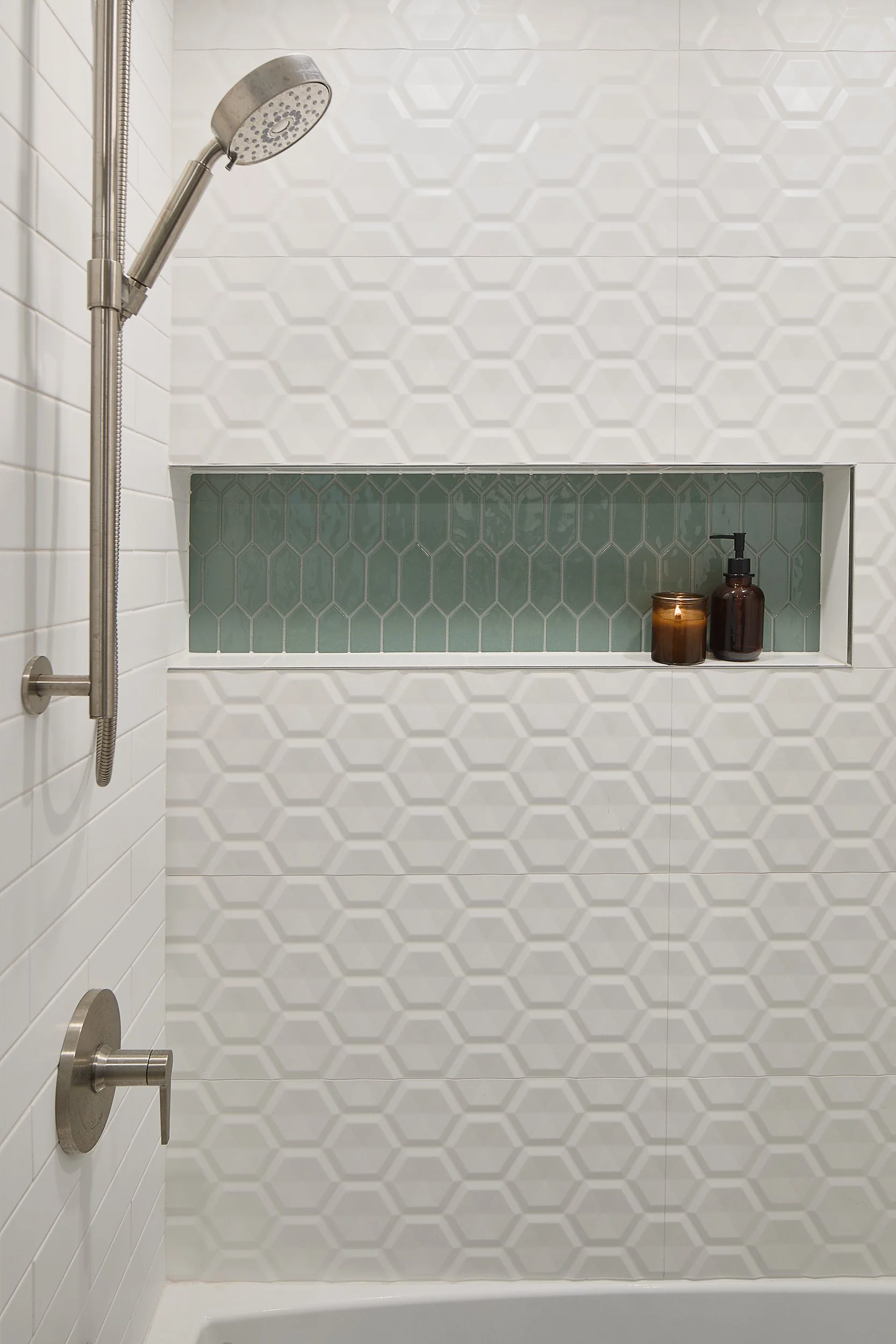 Custom shower remodel in Olympia, WA, featuring distinctive white custom tile, a built-in shower niche, and satin fixtures, installed by Brown Building Contractors.
