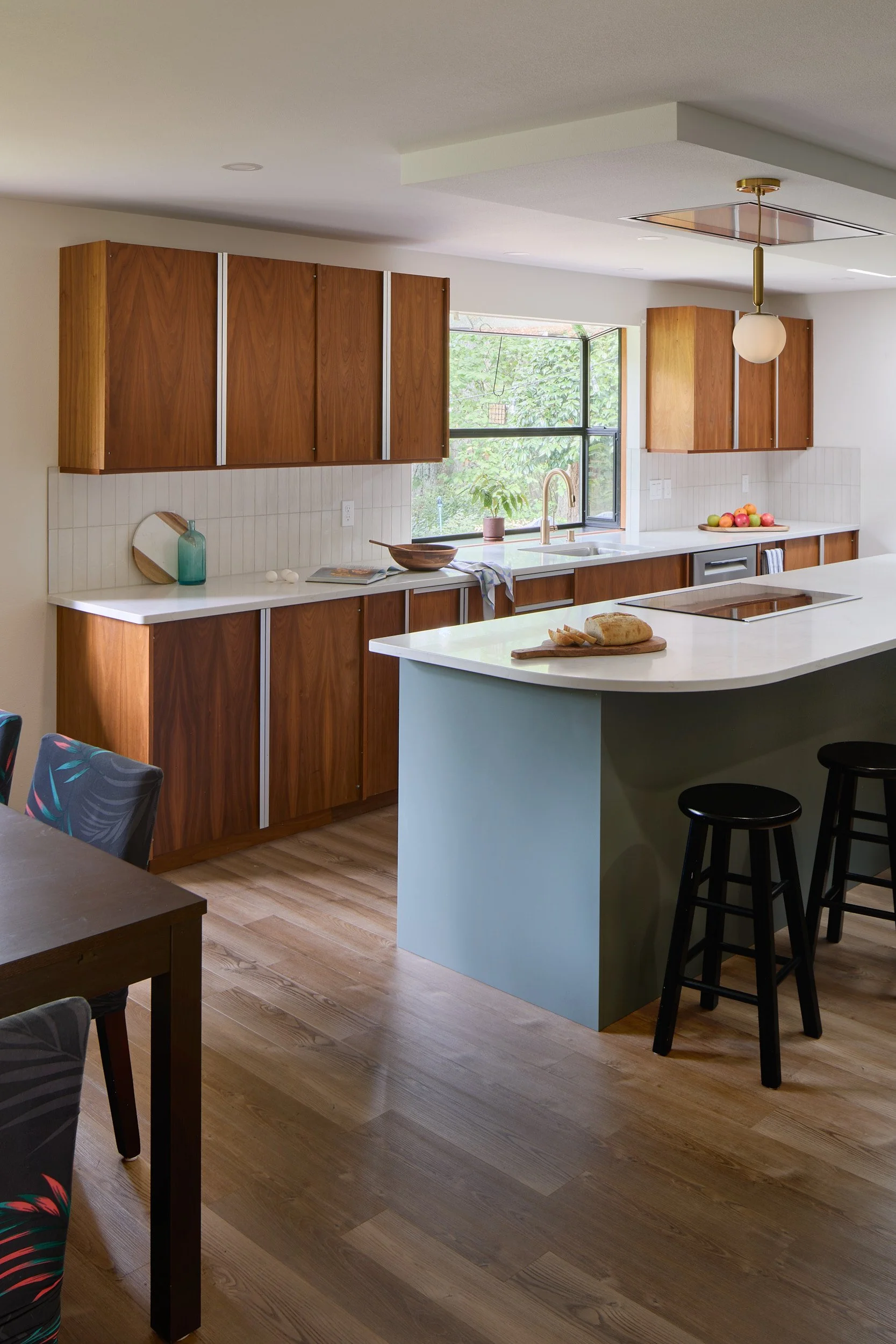 Interior featuring a mid-century modern kitchen and dining area, featuring custom lighting and cabinetry, from a residential remodel in Olympia, Washington, by Brown Building Contractors.