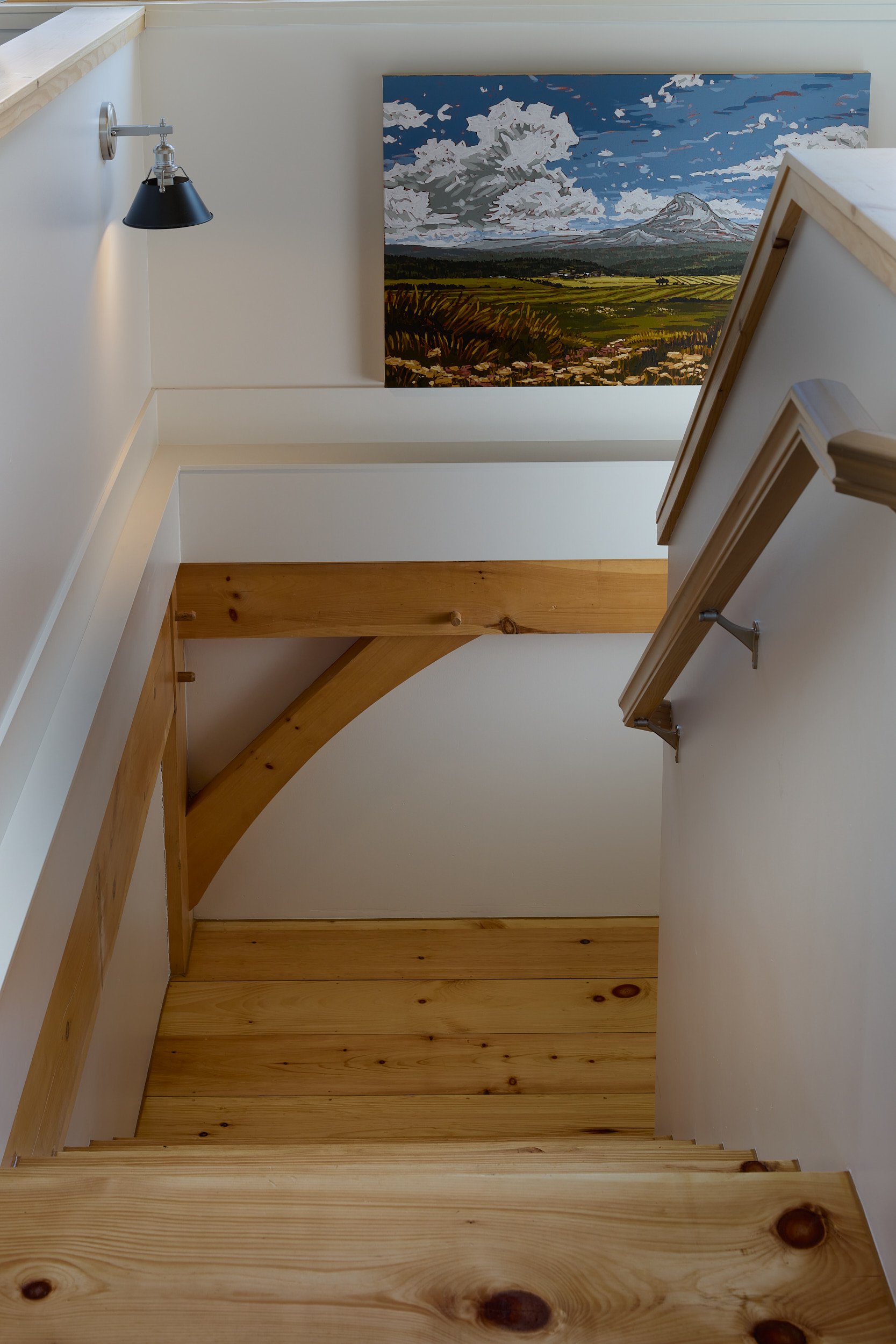 Exposed timber stairwell in the Rangeley Timber Frame Barn Home (Ridgefield, WA), featuring custom wood treads and balusters, built for The Barn Yard.
