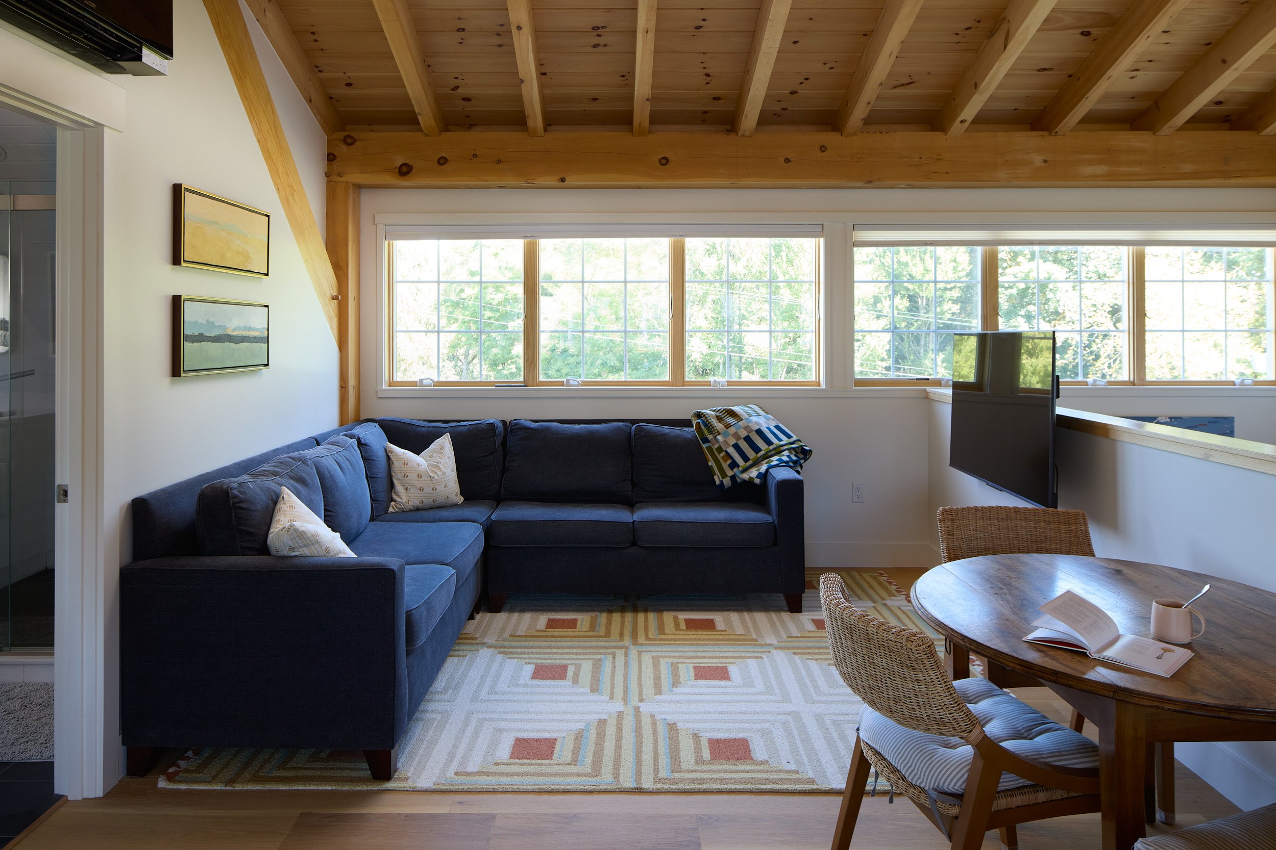Comfortable front room seating area in the Rangeley Timber Frame Barn Home (Ridgefield, WA), highlighting the exposed timber ceiling and natural light, built for The Barn Yard.