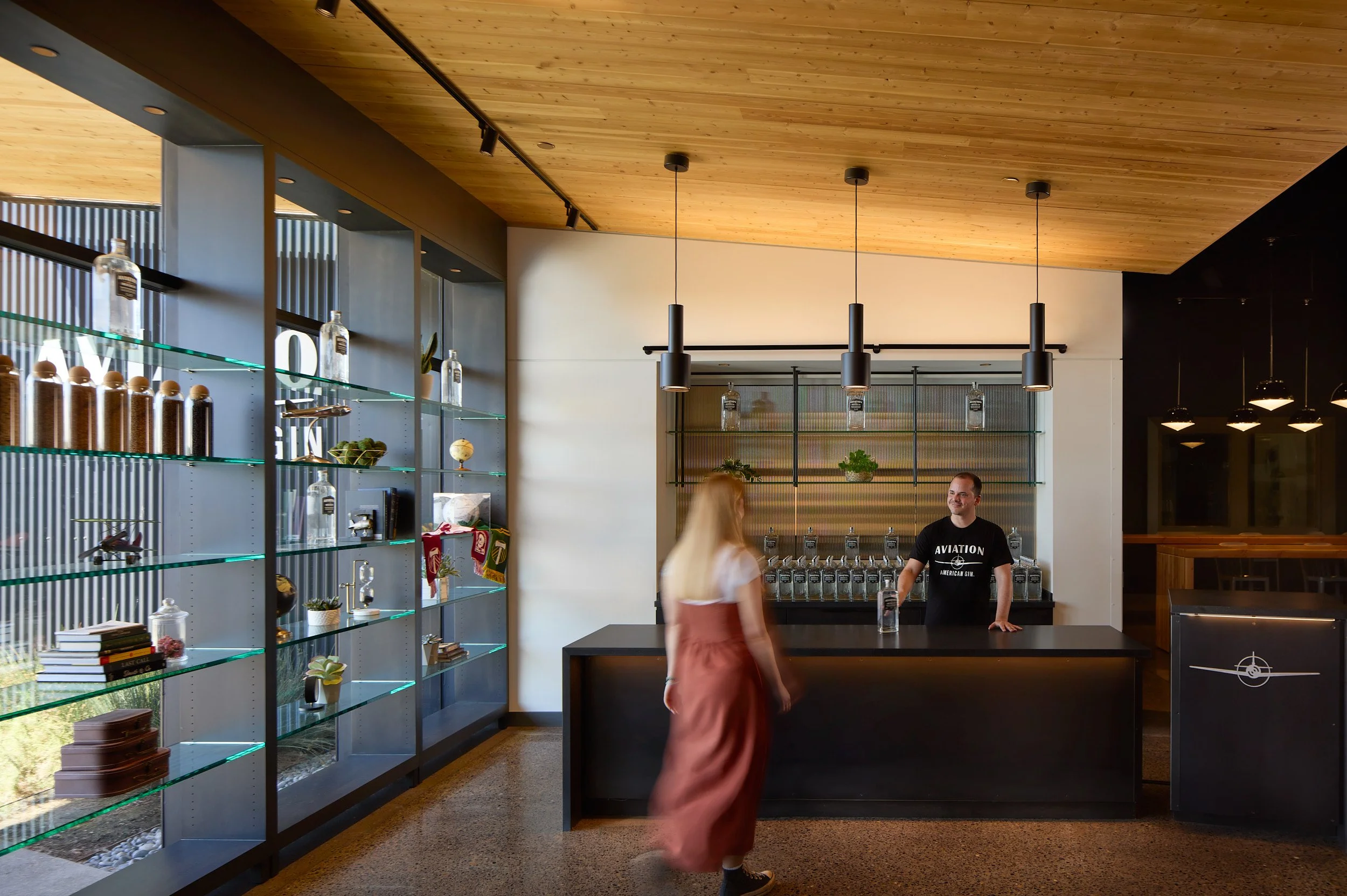 Interior architectural photography showcasing the front counter and bottle display at the Aviation Gin Distillery tasting room in Portland, Oregon.