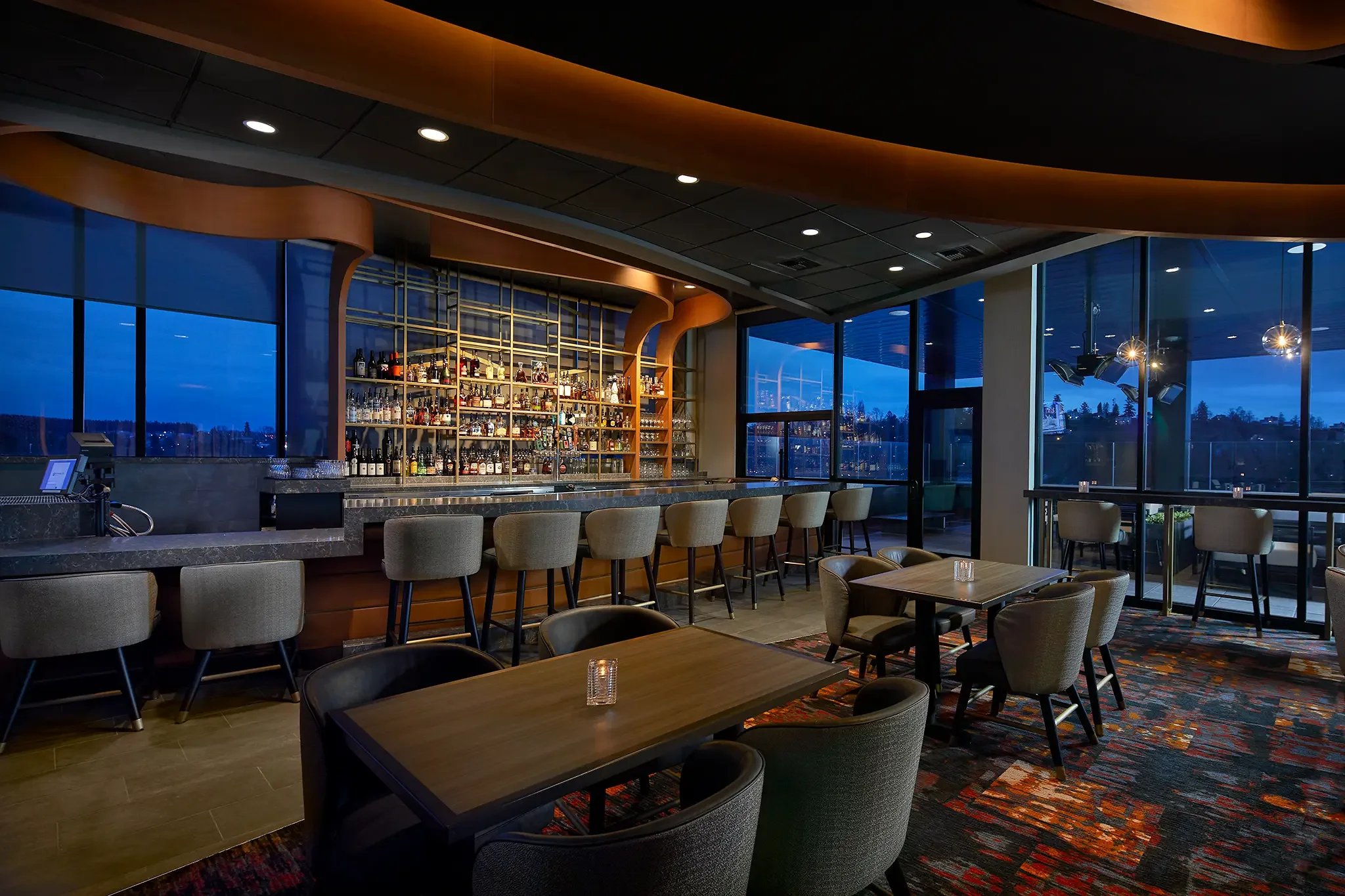 Slahal Steakhouse bar interior design captured at dusk, highlighting the custom bar and the Mt. Rainier view at the Emerald Queen Casino Hotel project by Cuningham Architects.