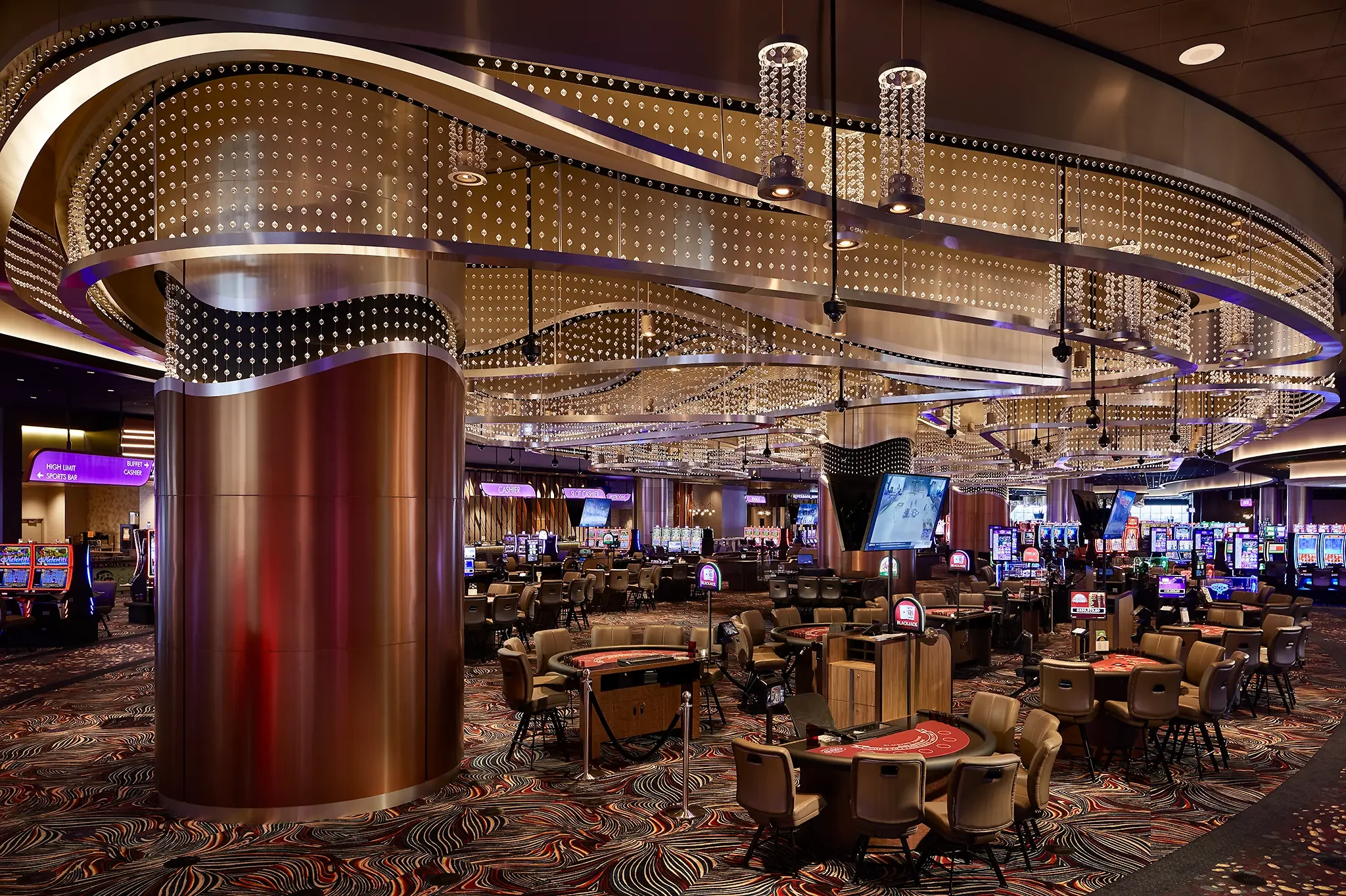Grand gaming room interior and main floor architecture at the Emerald Queen Casino, featuring a striking chandelier crystal art / lighting feature, designed by Cuningham Architects.