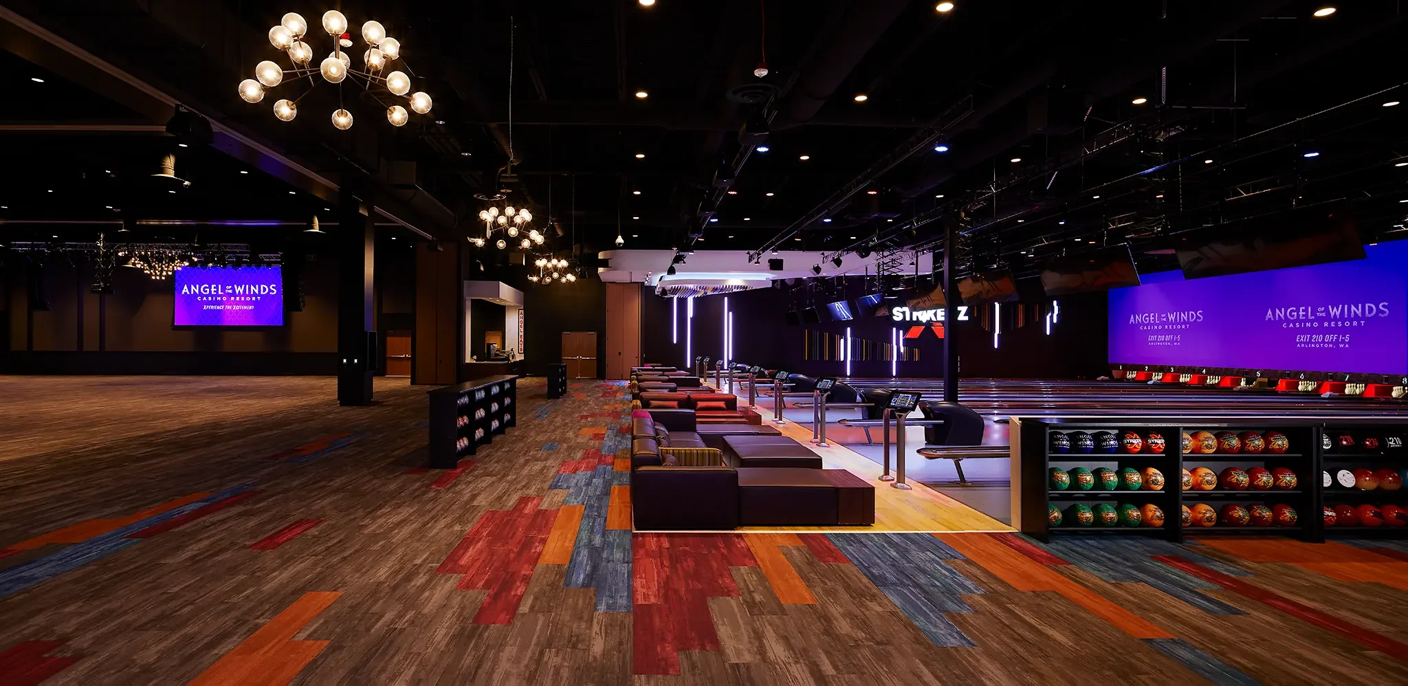 Interior of the Strikerz Bowling alley lounge with vibrant lighting and accompanying meeting and event area at Angel of the Winds Casino Resort