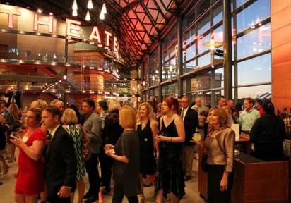 a crowd of people holding drinks inside a museum