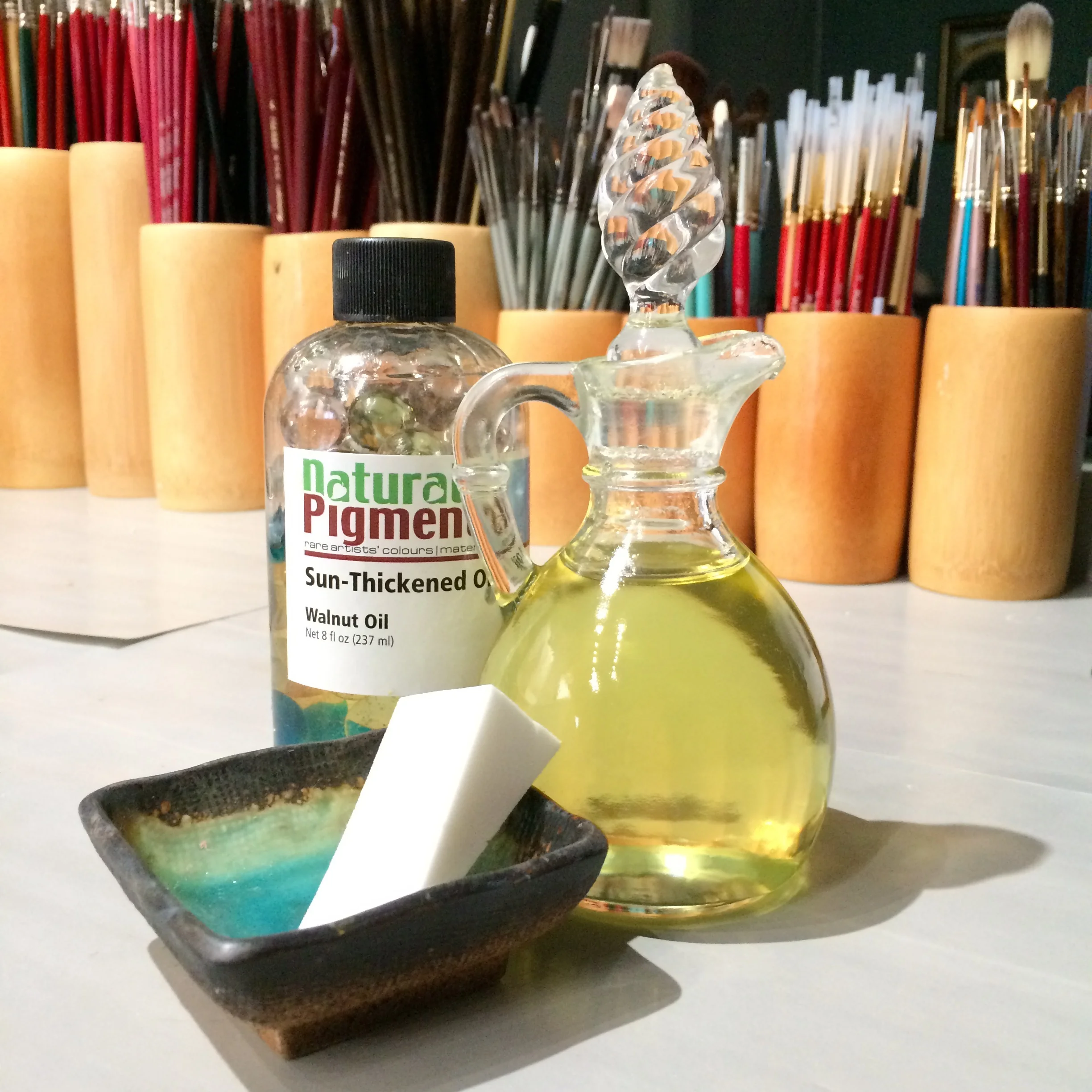brushes, walnut oil in a bottle and glass jar, cosmetic sponge in a dish.