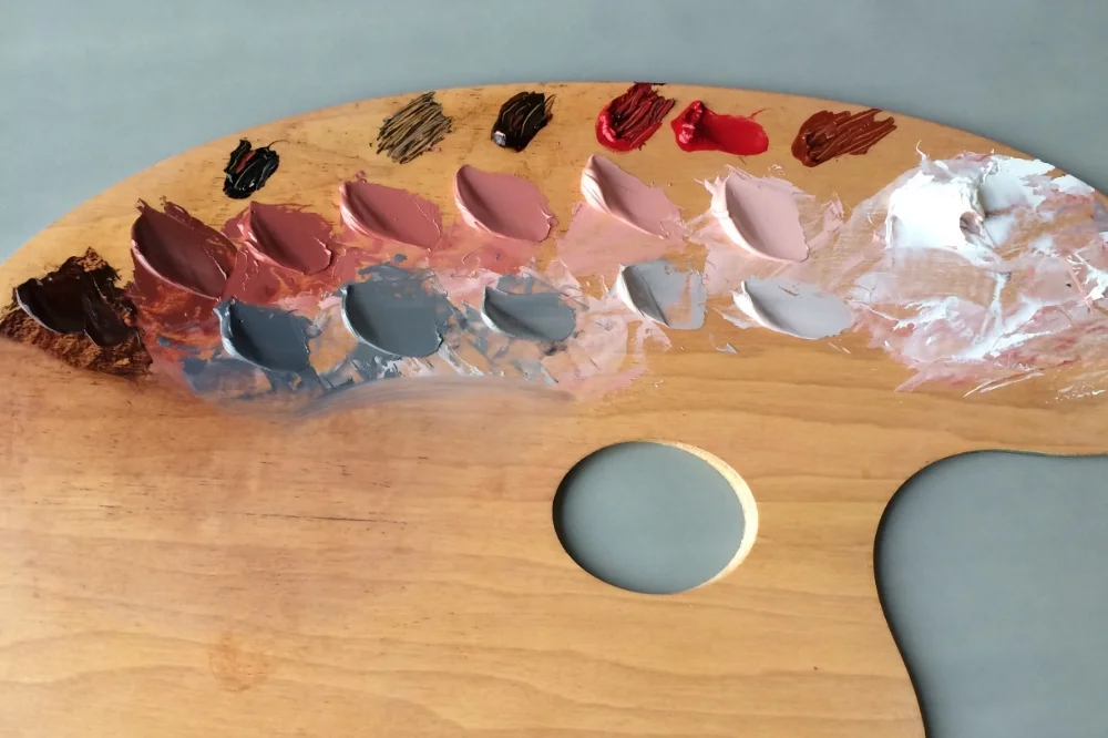 A palette with multi colored globs of paint.