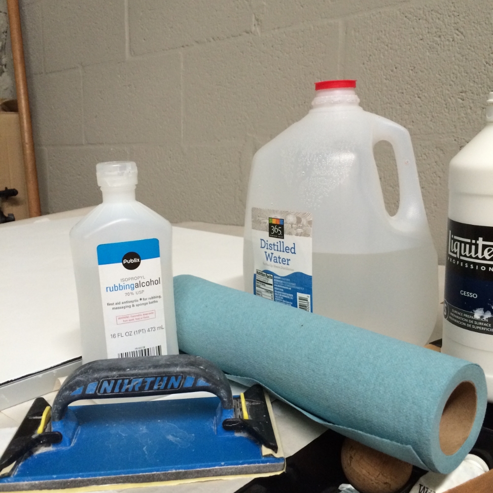 distilled water, rubbing alcohol, sand paper gesso and blue paper towels.