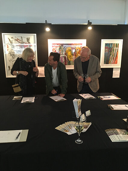 Silent auction bidders with artist Guy Seanyear (middle)