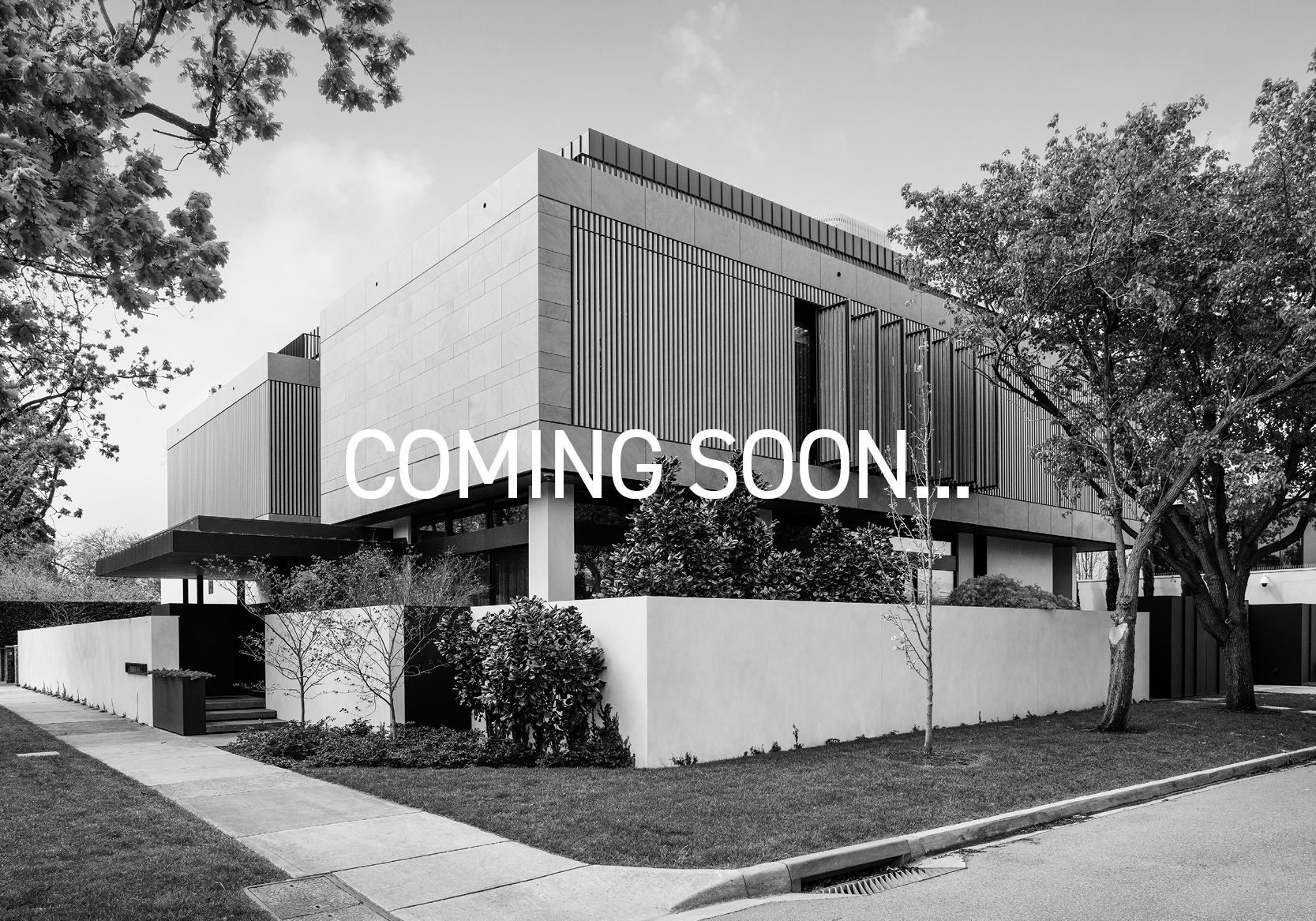 Black and white photo of a modern house with the words 'Coming Soon!' displayed across the front.