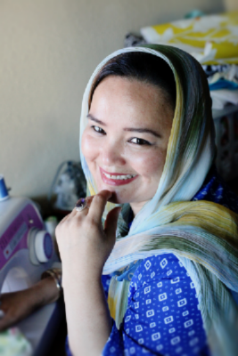 Khatera at her sewing desk in her home where she works. (Photo credit to J ane Marie Photography)