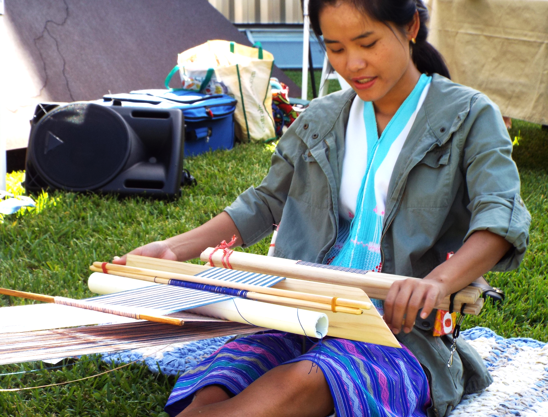 Sa Nay Ma demonstrating the art of creating scarves with a back-strap weaving loom.