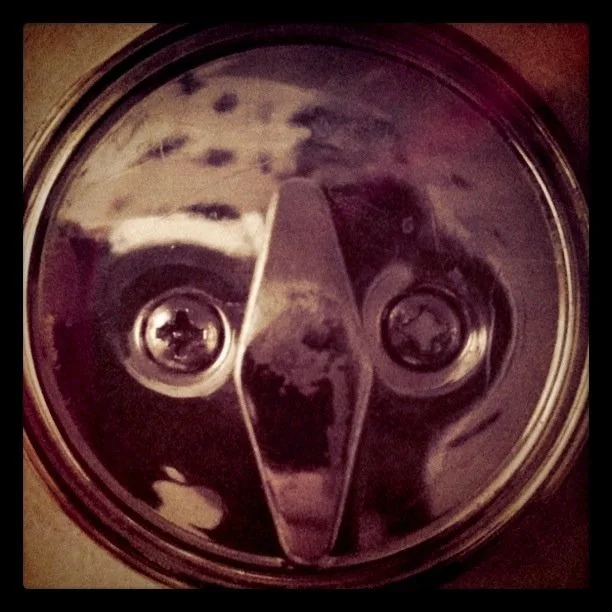 Close up of a deadbolt lock knob, vertical between two screws on it, looking like a face.
