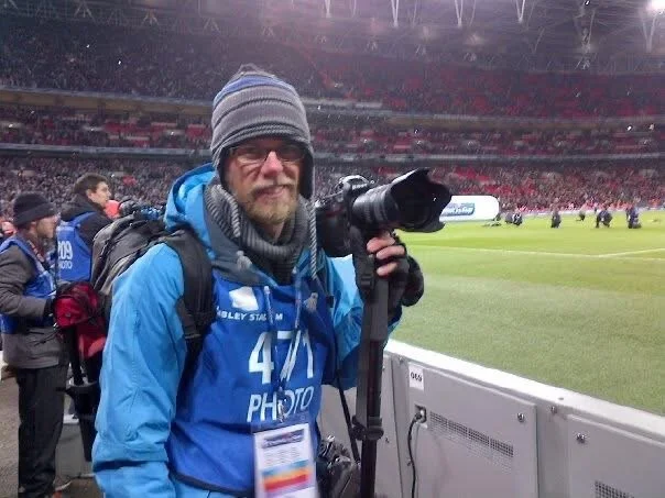 Photographer with camera at a sports stadium during a game.