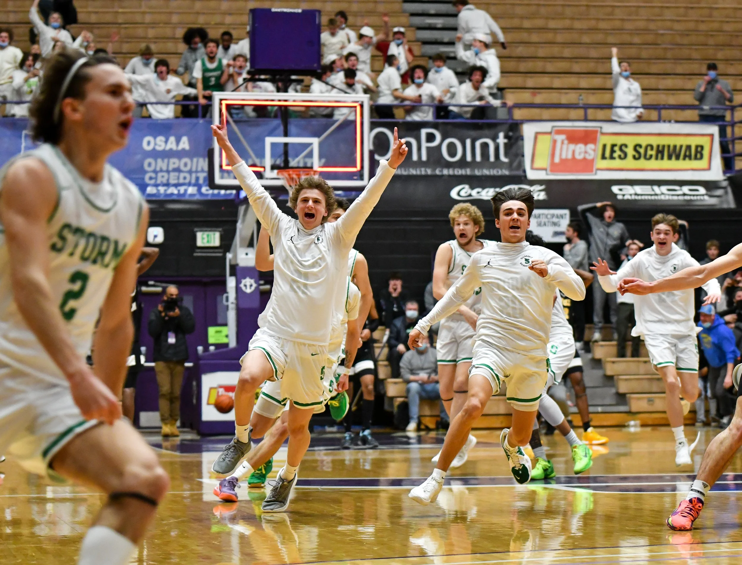  Summit High School players celebrate and chase senior Julian Mora, left, after Mora hit a game-winning putback shot as time expired to send the Storm to the 6A OSAA state tournament semifinals on March 9, 2022, at the Chiles Center at the University