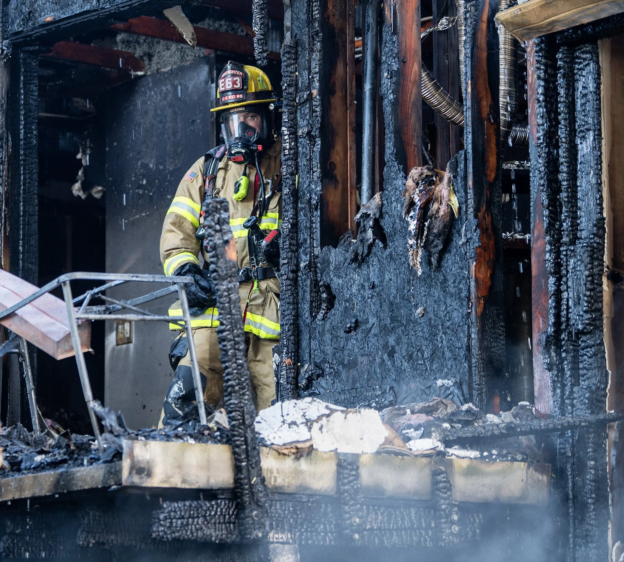 A firefighter stands near the back patio of a burned apartment unit Tuesday June 11, 2024, at the site of a three-alarm fire at the Erica Village apartment complex in Hazel Dell. 