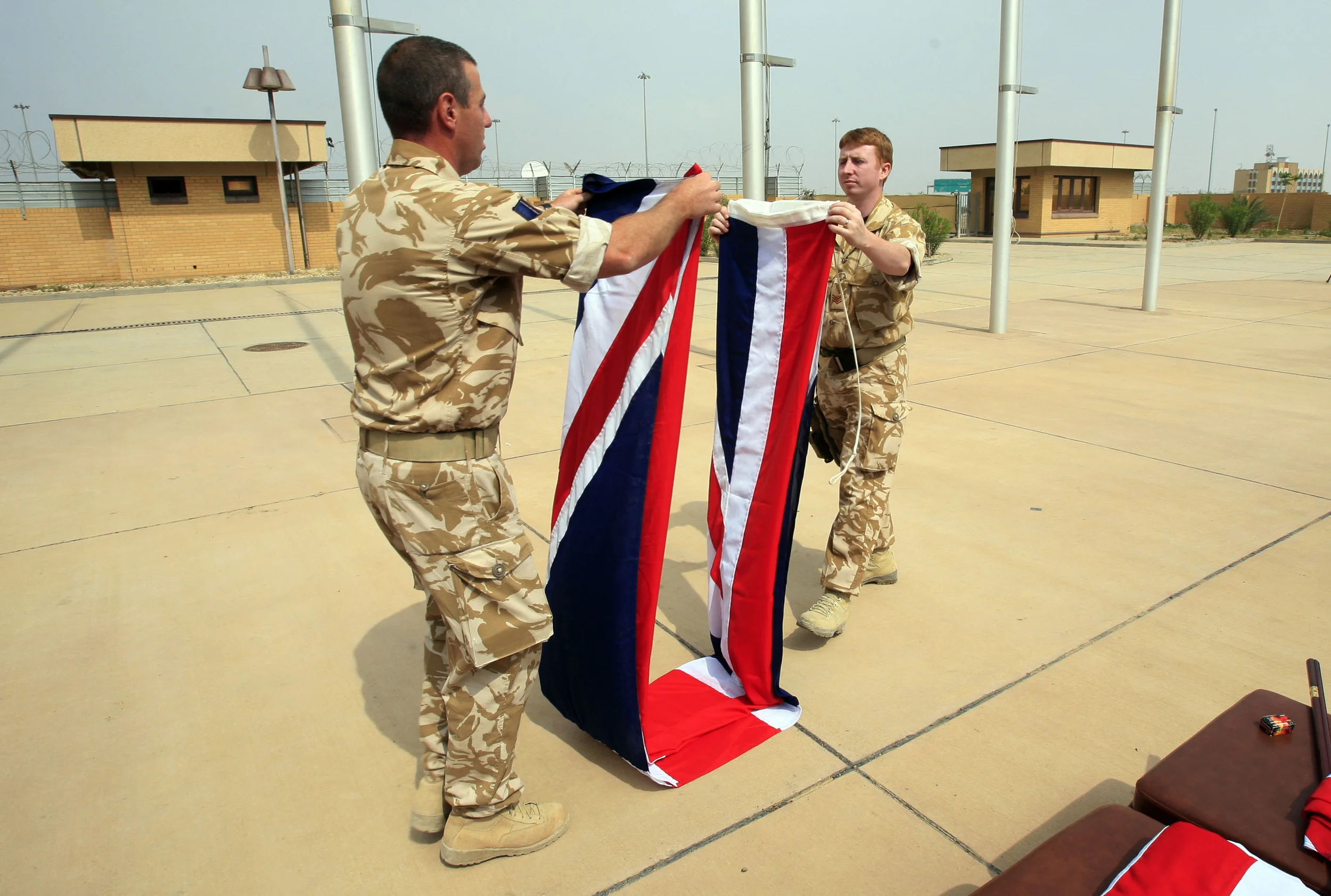  British soldiers fold away the Union flag following a 'Transfer of Authority' ceremony at the main coalition base at Basra airport, Iraq. The British handed over power to their U.S. partners, April 2009. 