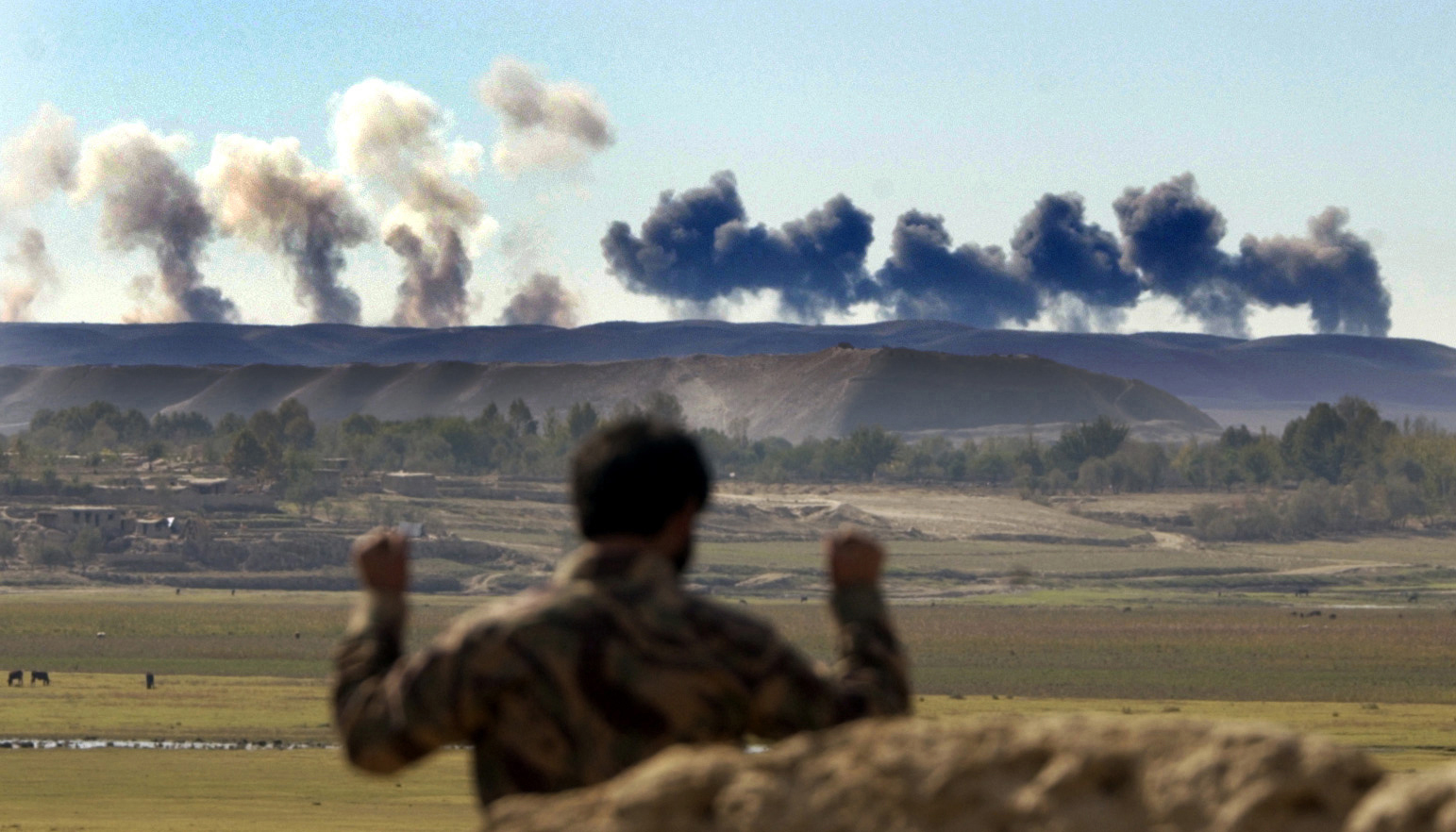 An Afghan Northern Alliance soldier watches the bombardment by U.S. B-52's, of a ridge occupied by Taliban, near Khoja Bahauddin, Afghanistan, October 2001.